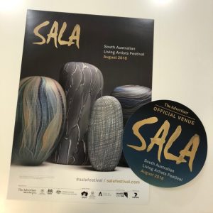 Image of the SALA 2018 poster and sticker. The poster features the work of Clare Belfrage's glass works.
