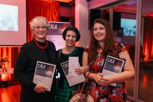 three women holding framed certificates.